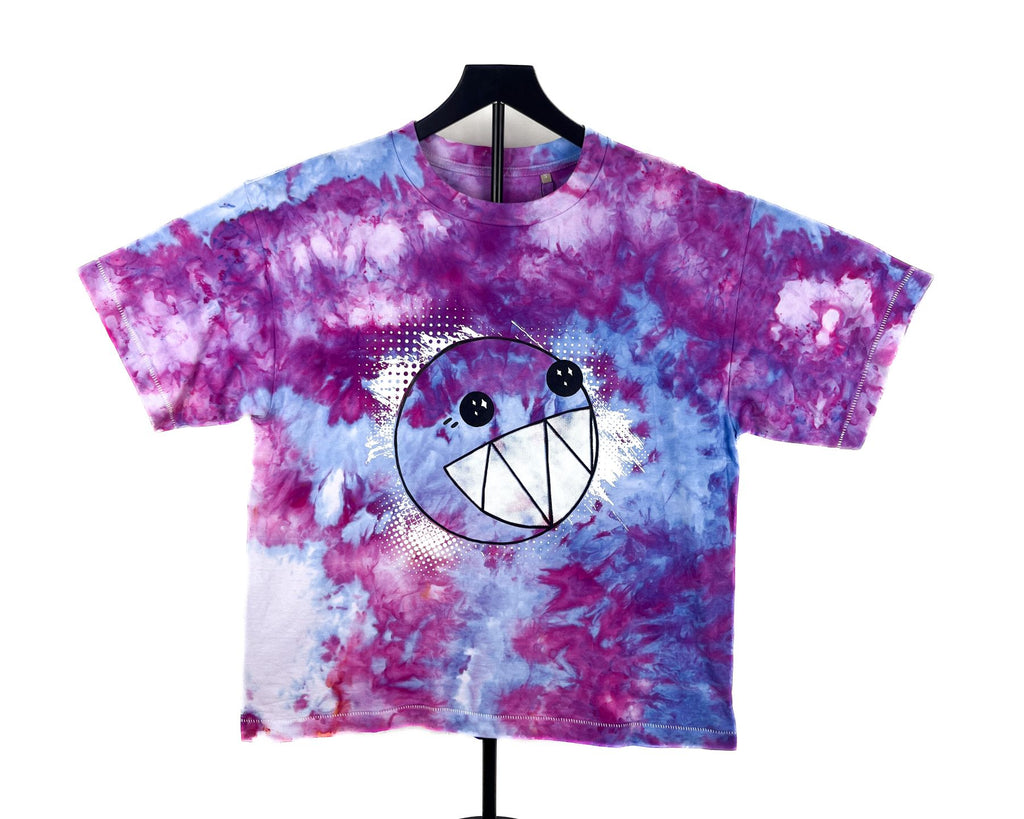 A short-sleeve tie-dye t-shirt on a black hanger, featuring a purple, pink, and blue watercolor pattern with a central cartoon smiley face graphic.