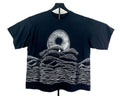 A black short-sleeve t-shirt displayed on a hanger against a white background, featuring a white graphic print of a Shai-hulud mouth from Dune and layered soundwave-style hills.