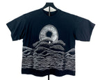 A black short-sleeve t-shirt displayed on a hanger against a white background, featuring a white graphic print of a Shai-hulud mouth from Dune and layered soundwave-style hills.