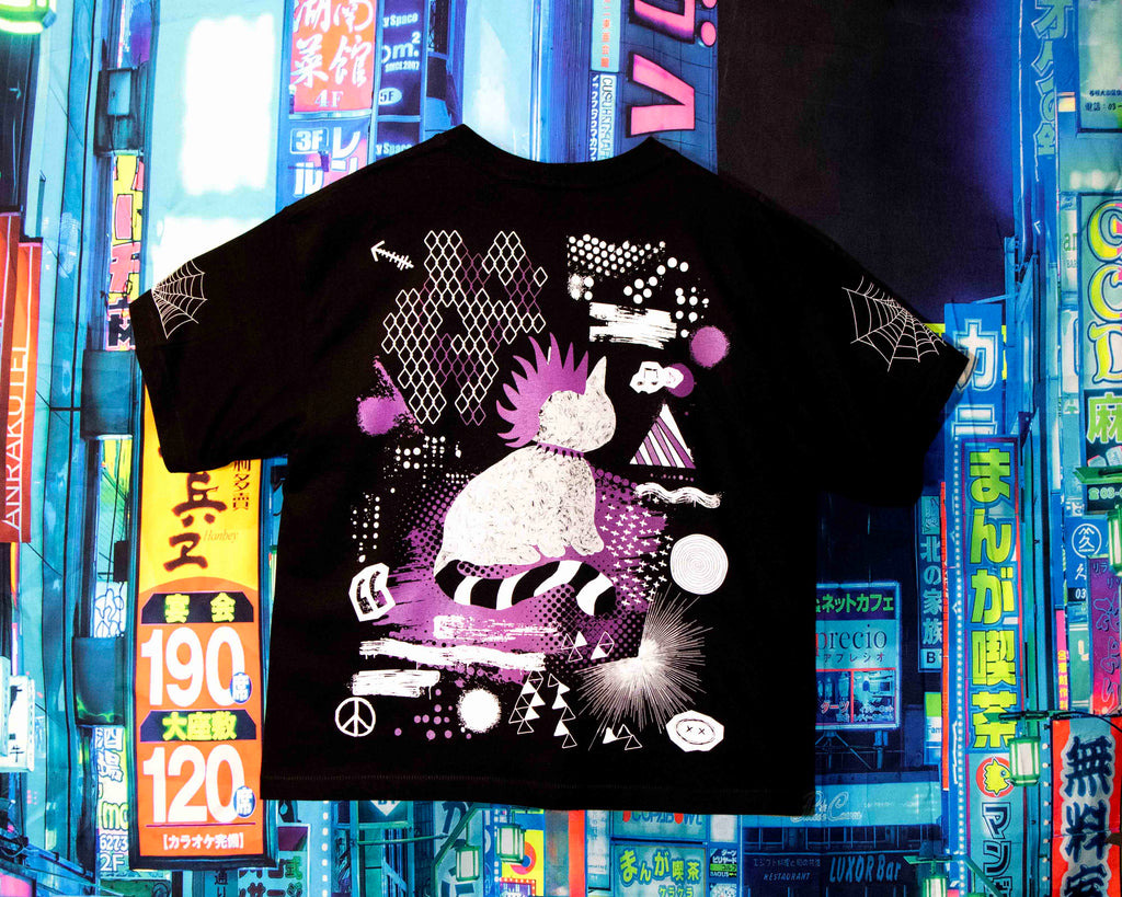 Black t-shirt with a unique design in front of colorful bookshelves