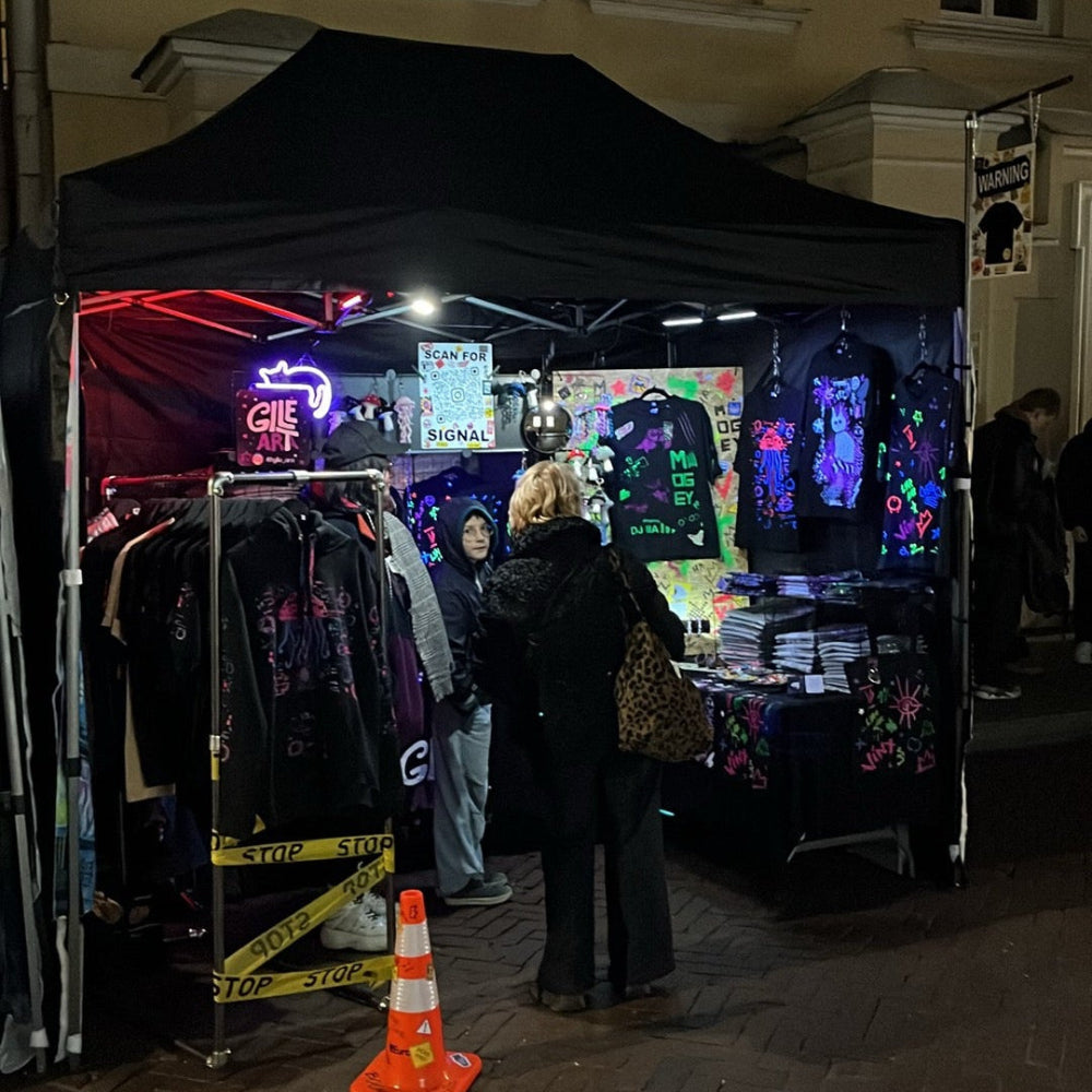 Dark tent with colorful displays and people around at night.