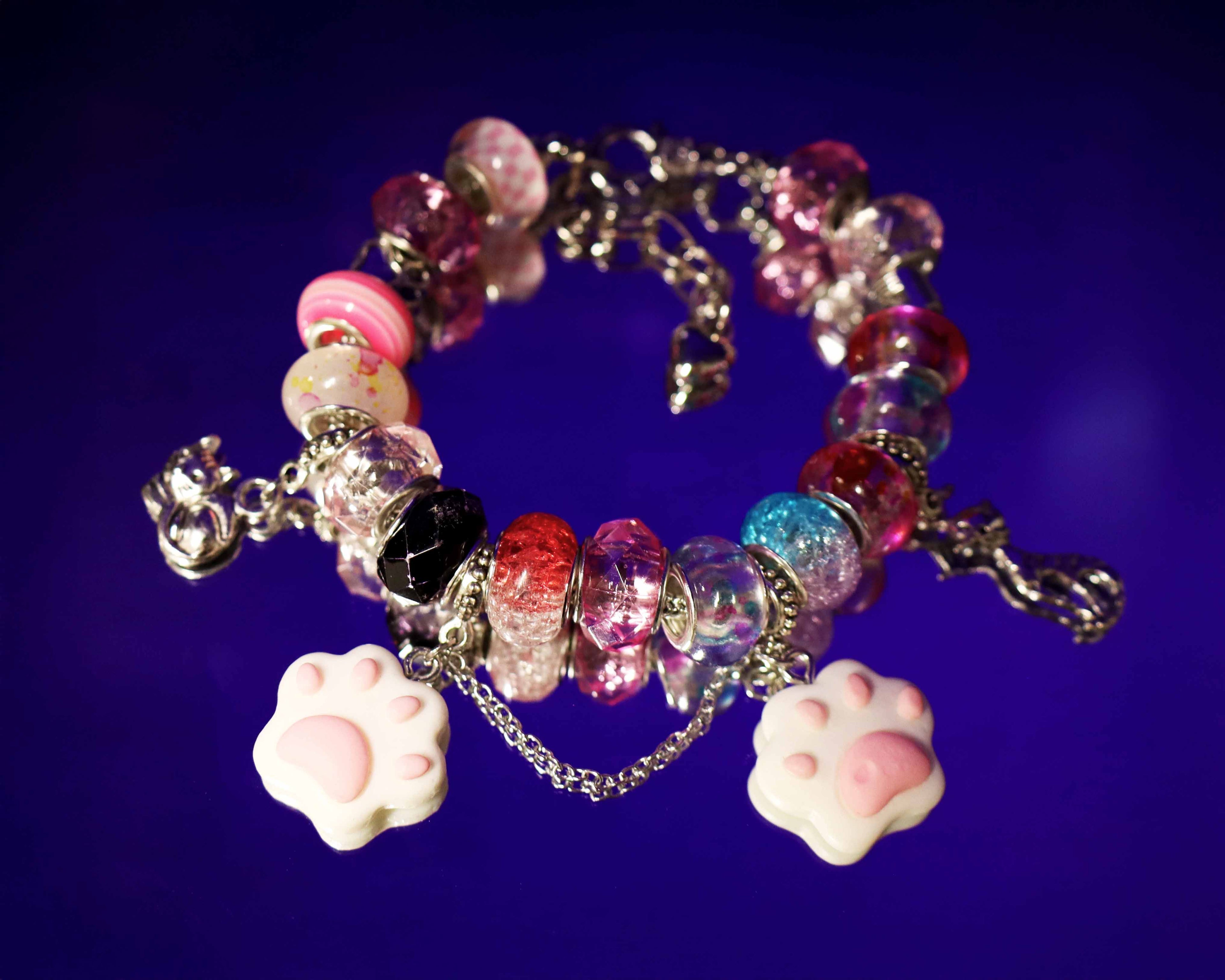 Colorful beaded bracelet with paw charm on a dark blue background