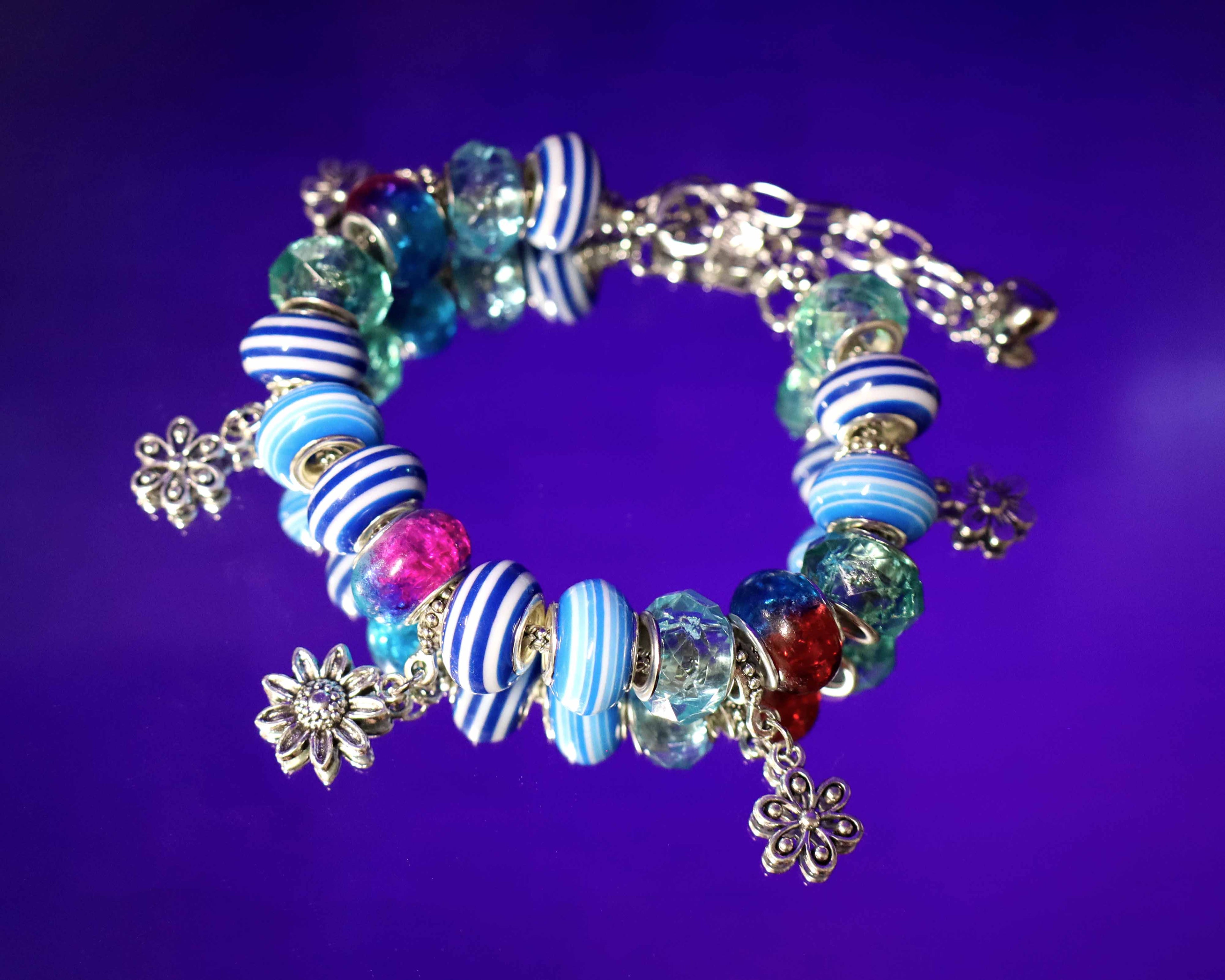 Colorful beaded bracelet with floral charms on a purple background