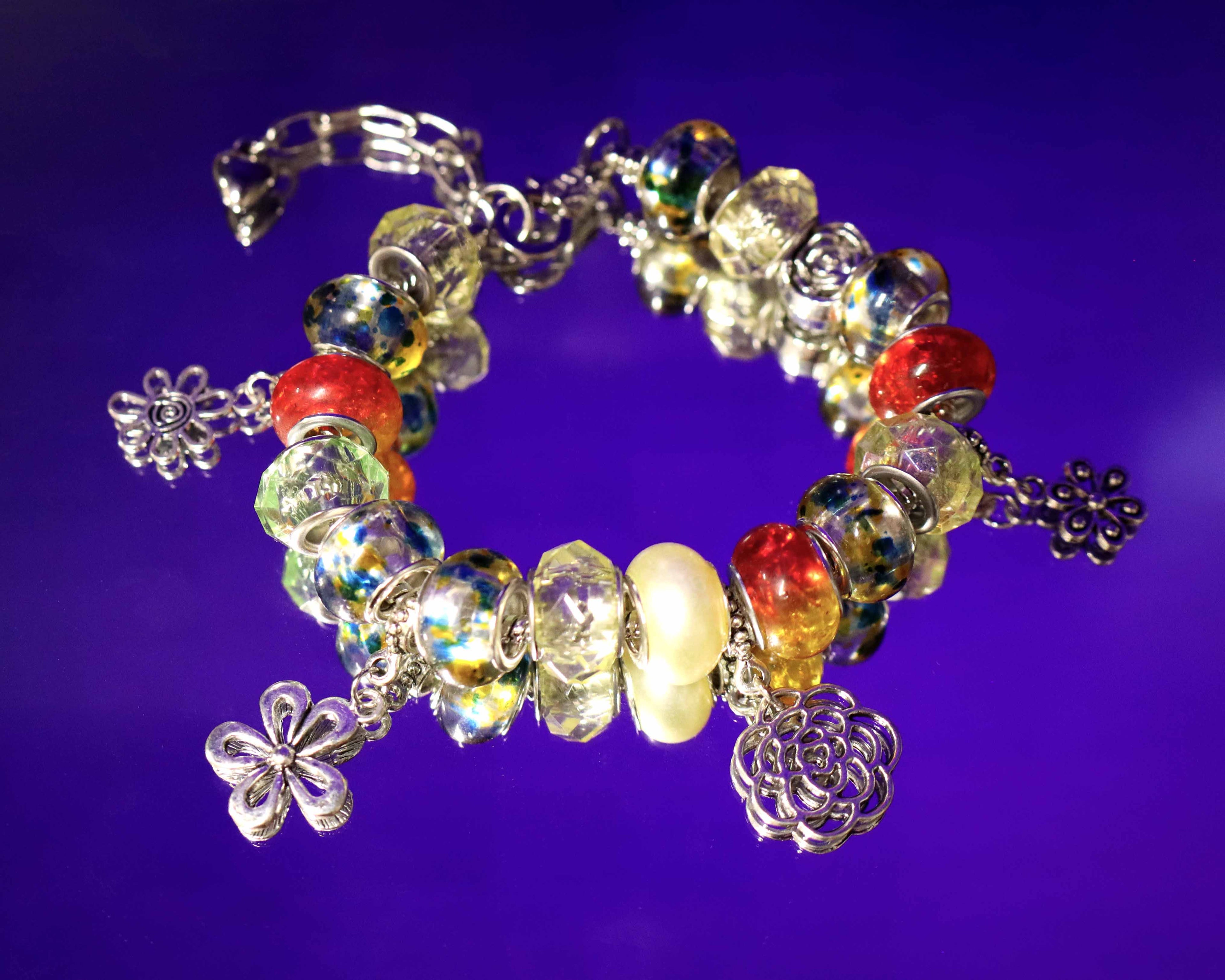 Colorful beaded bracelet with floral charms on a purple background