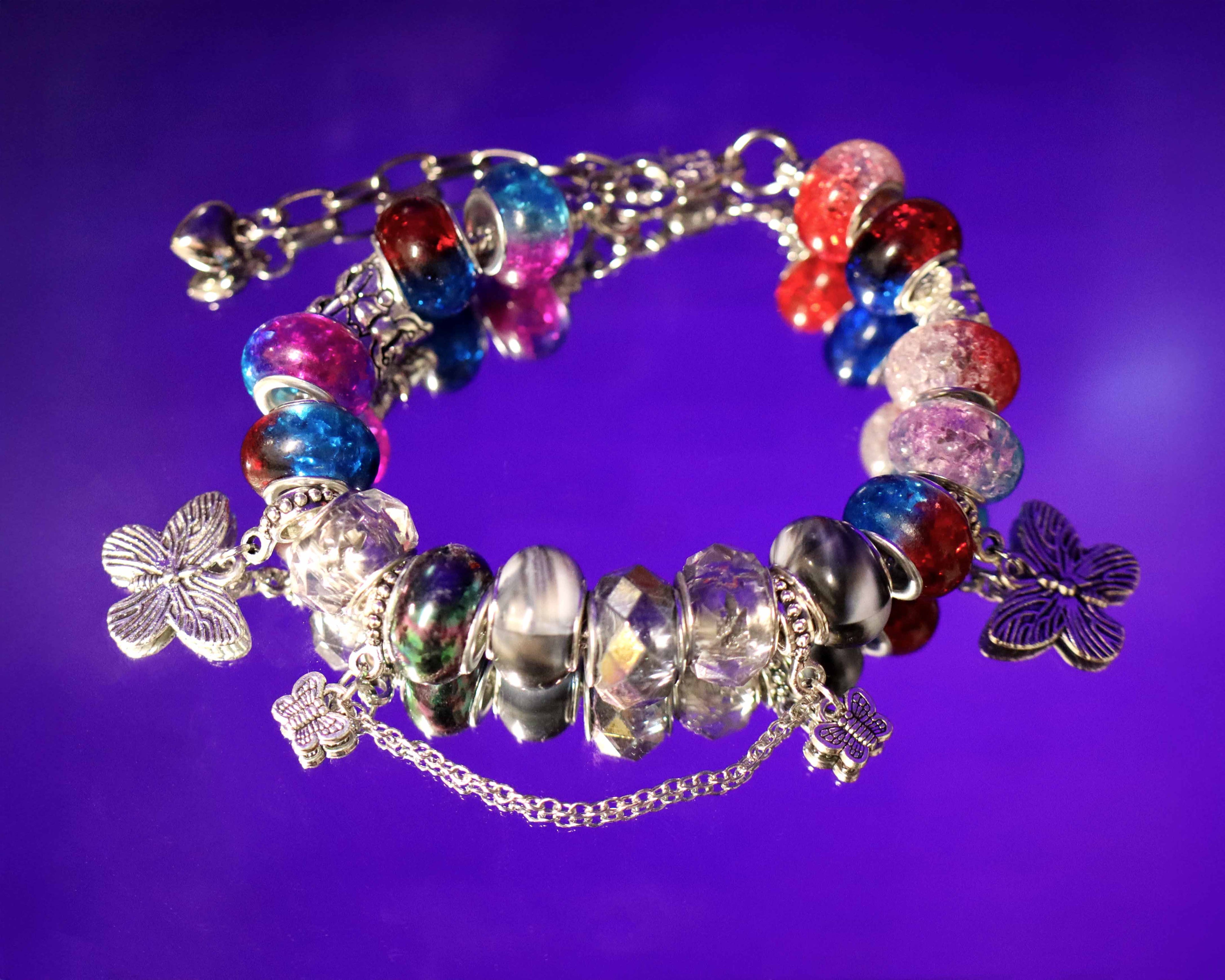 Colorful beaded bracelet with butterfly charms on a purple background