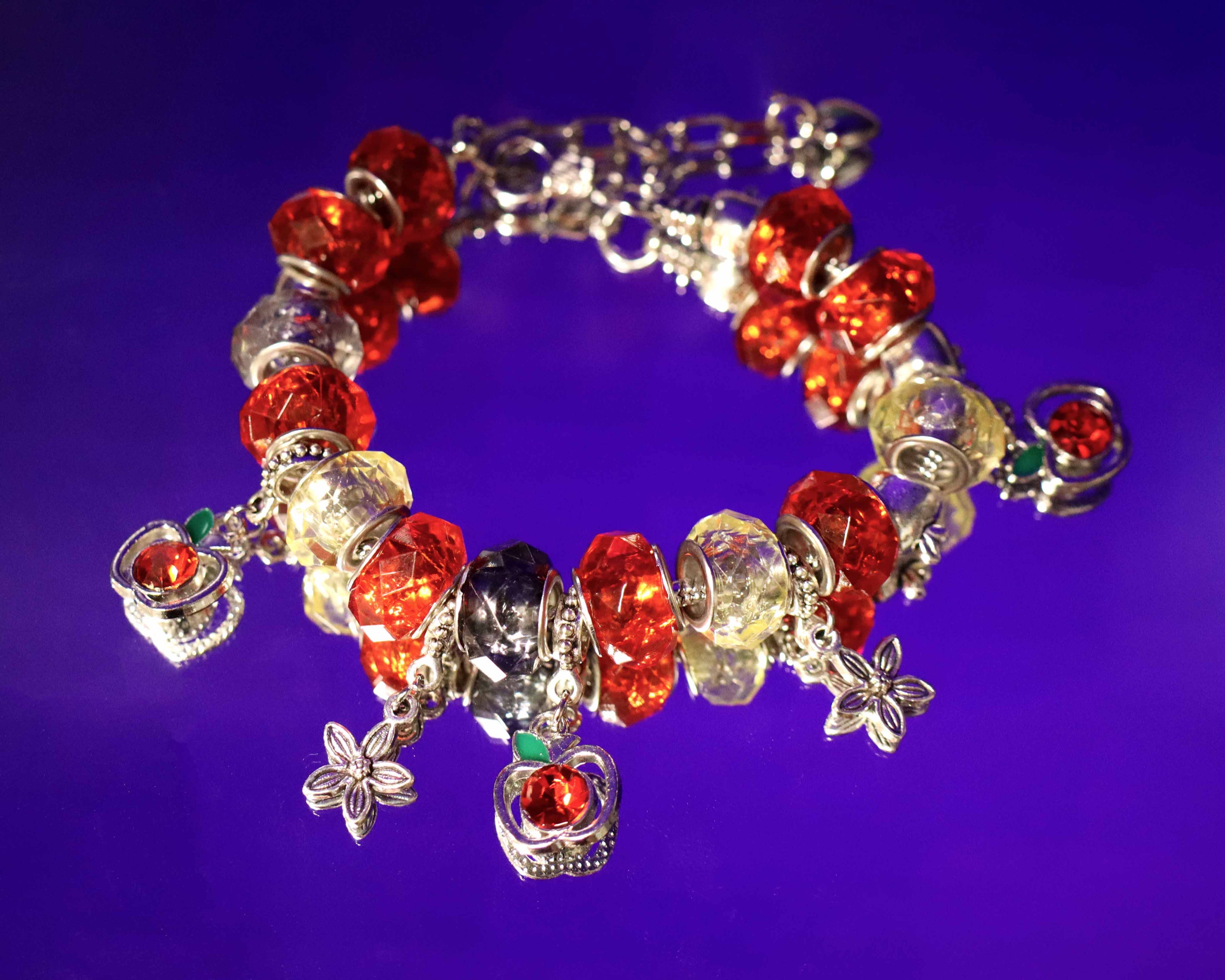 Bracelet with red, clear, and silver charms on a purple background