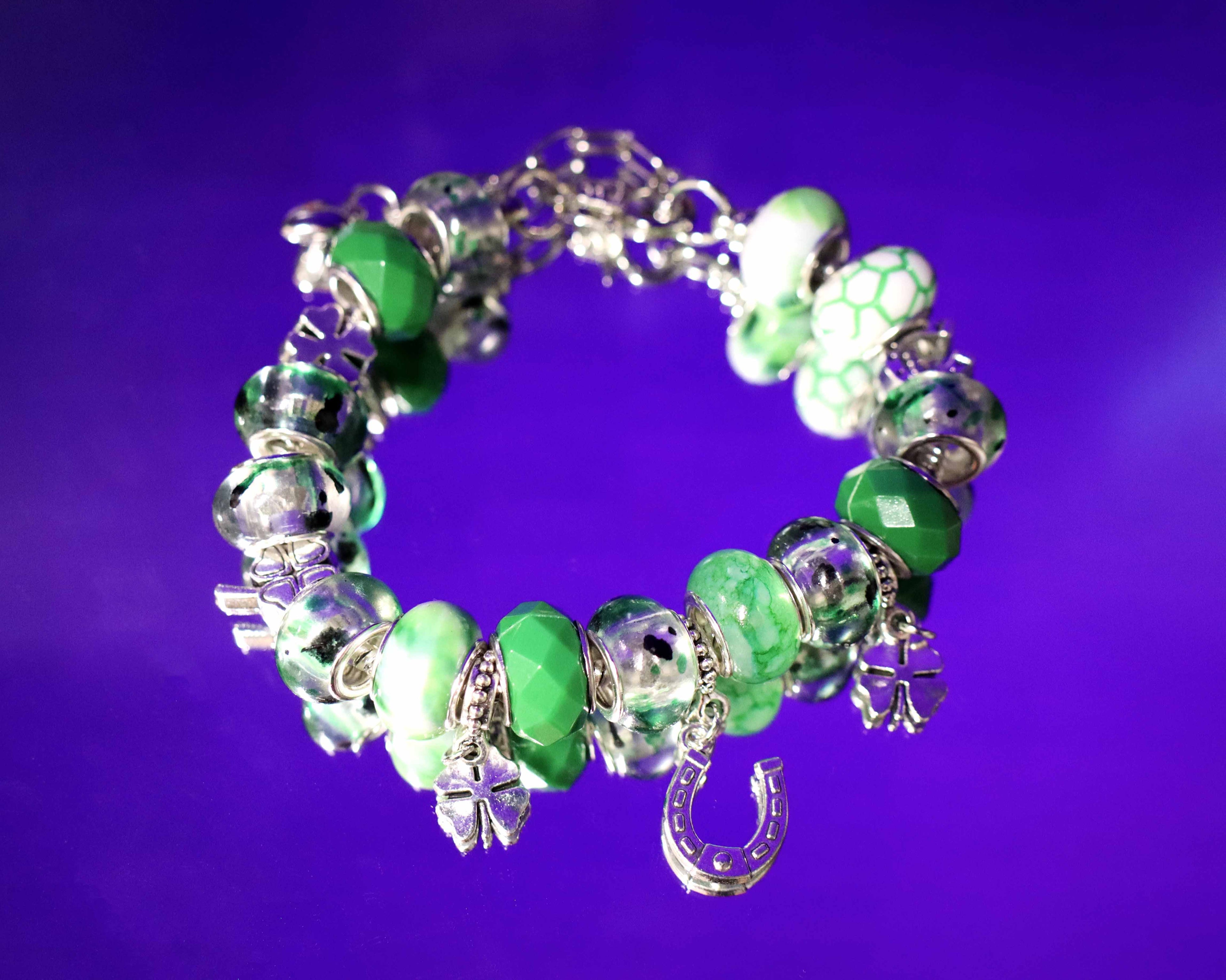 Green beaded bracelet with silver charms on a purple background