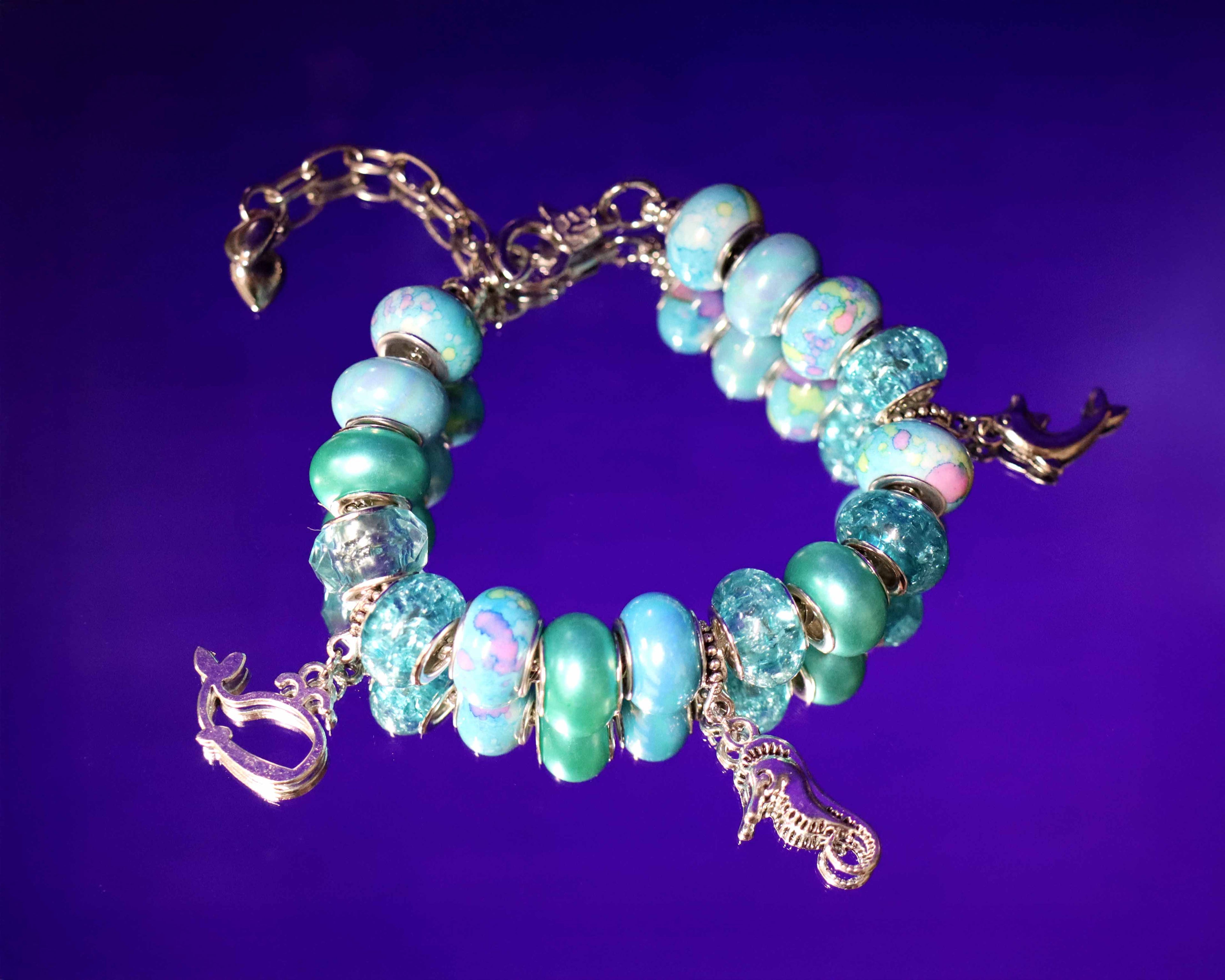 Turquoise beaded bracelet with gold charms on a purple background