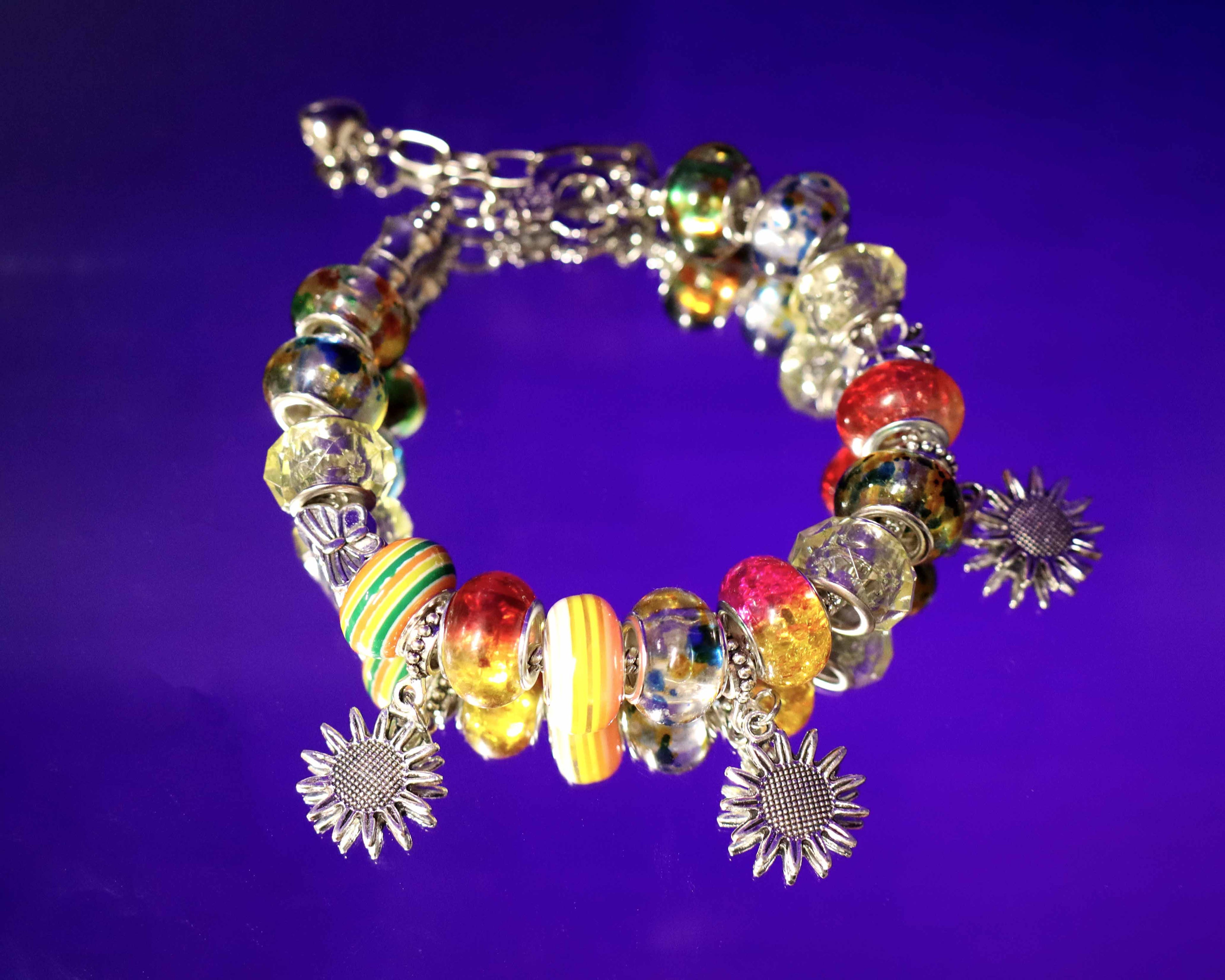Colorful beaded bracelet with sunflower charms on a purple background