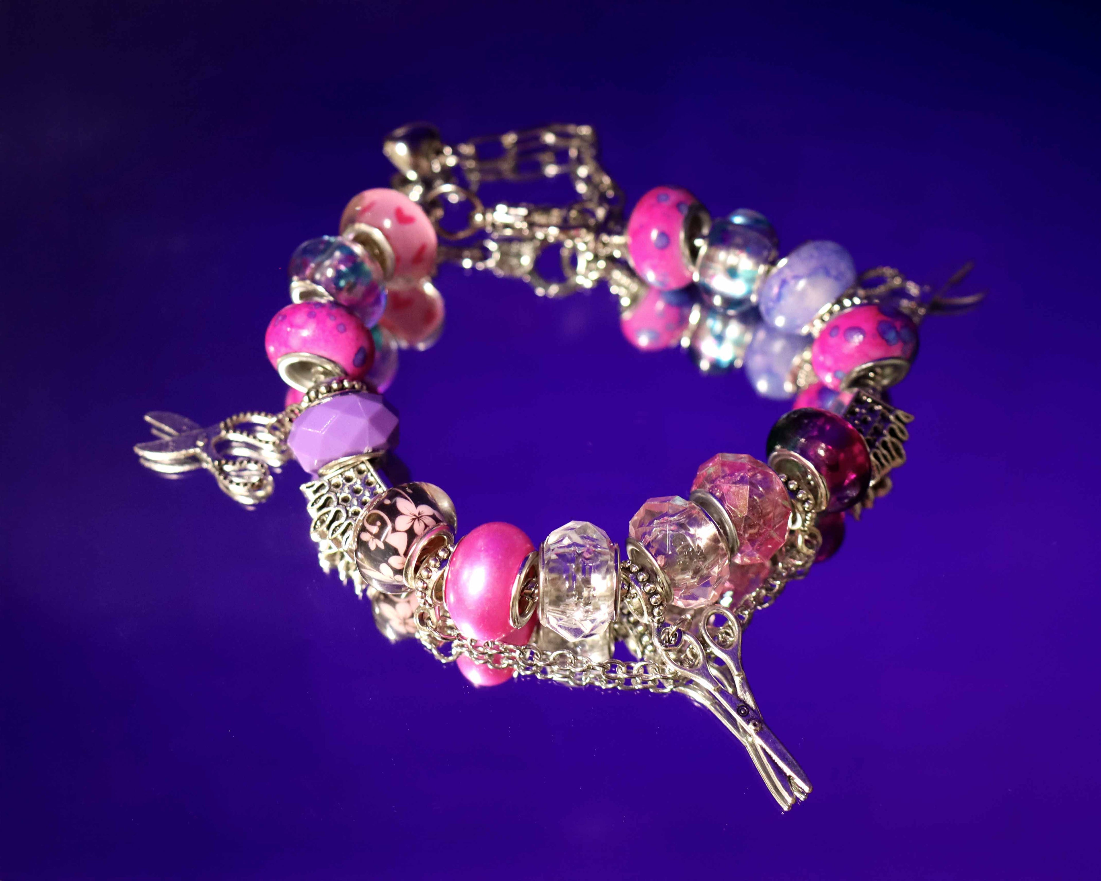 Bracelet with pink and purple beads and charms on a purple background