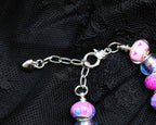 Bracelet with pink and purple beads on a black textured background