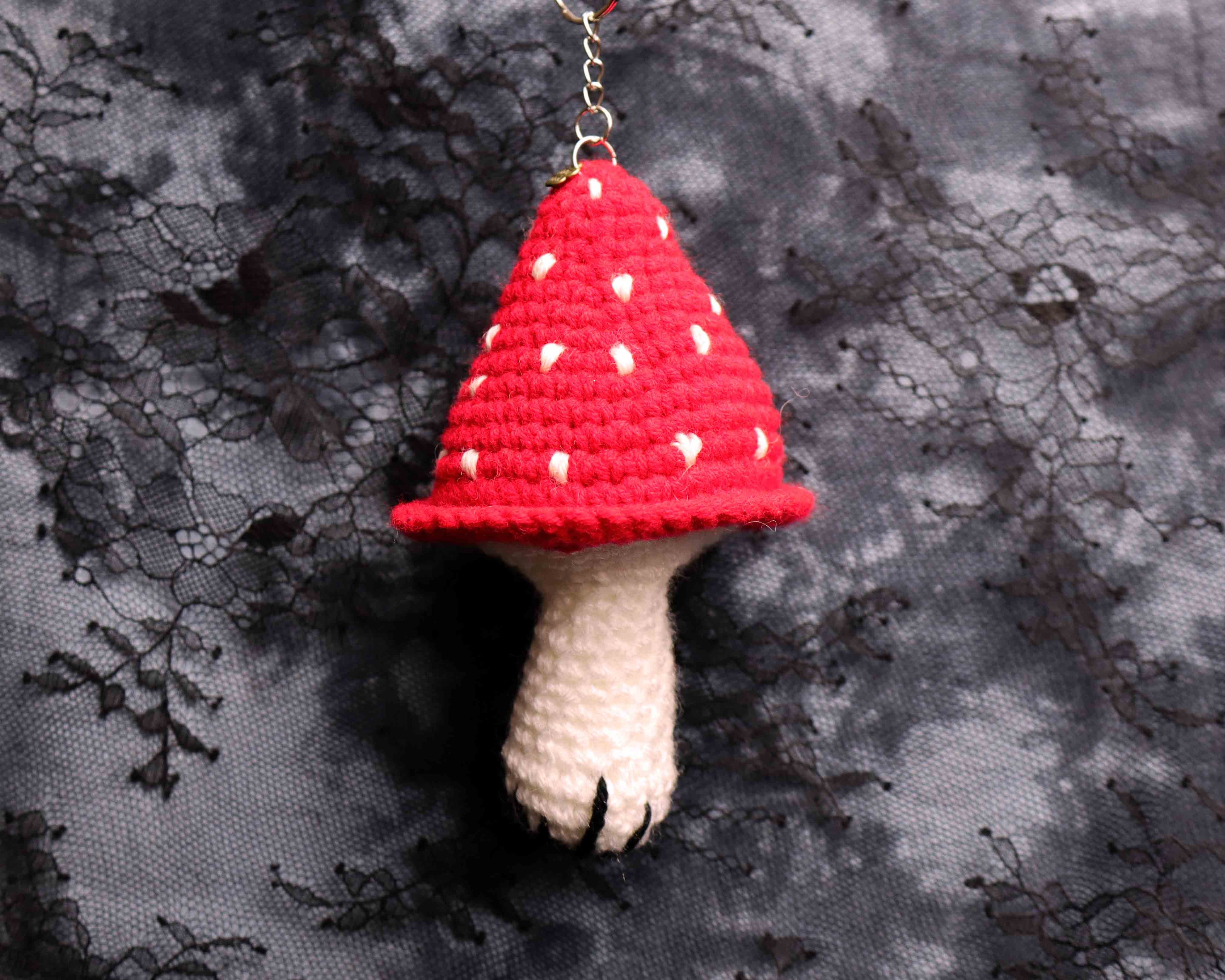 Red and white mushroom-shaped keychain on a textured black and gray background