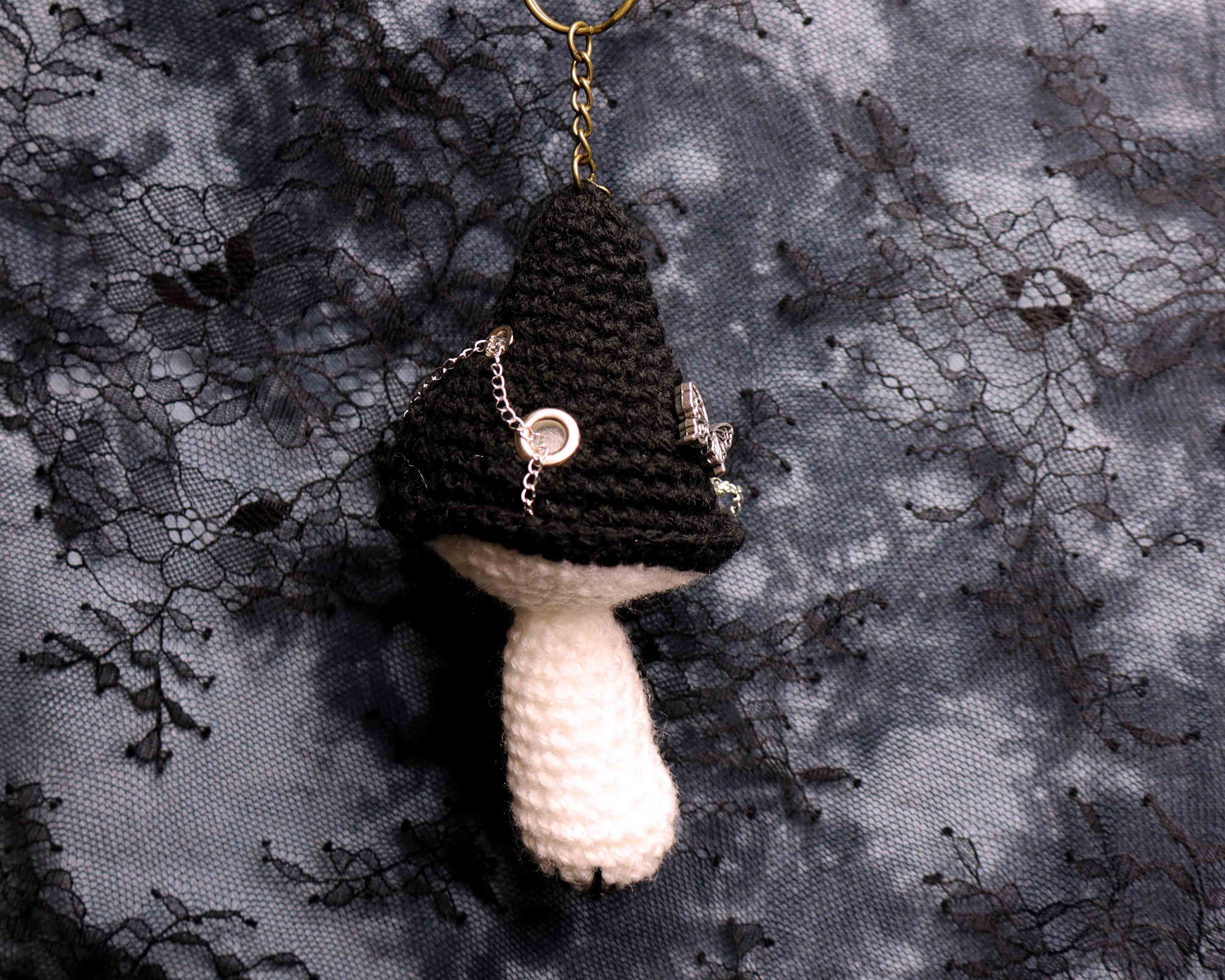 Crocheted mushroom keychain on a textured black and gray background