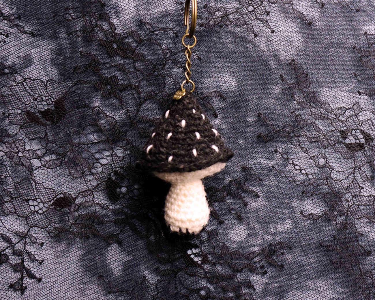 Crocheted mushroom keychain on a lace fabric background
