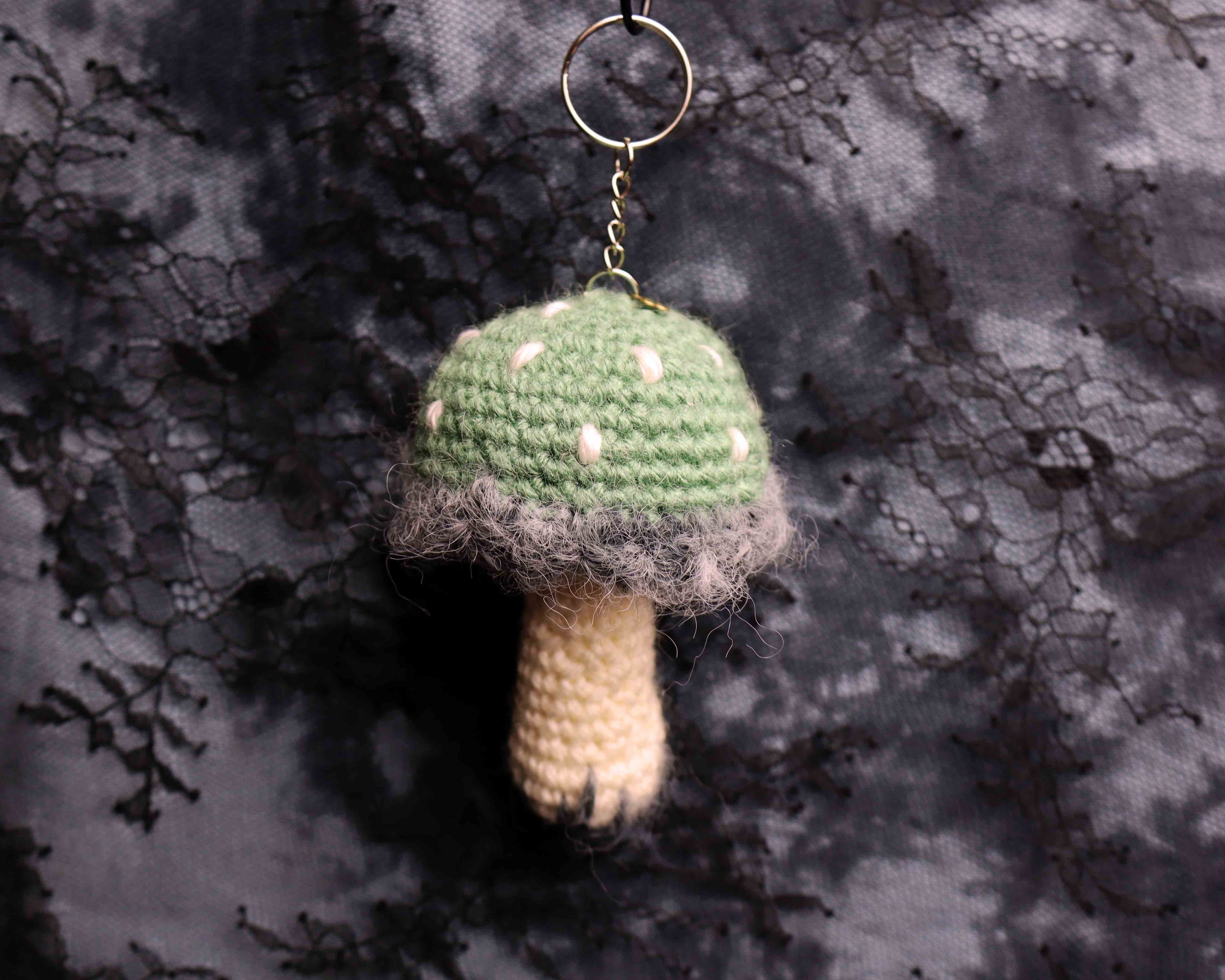 Crocheted mushroom keychain on a textured dark background