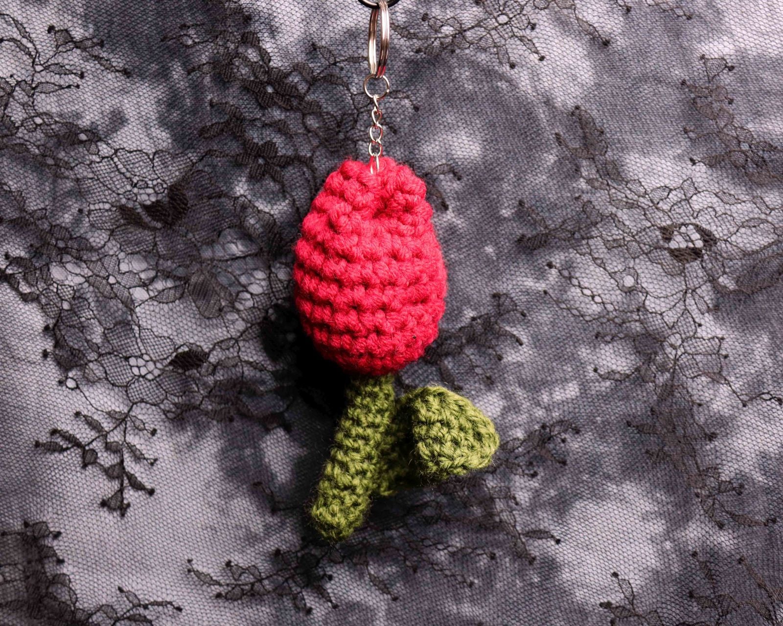Crocheted rose keychain on a textured fabric background