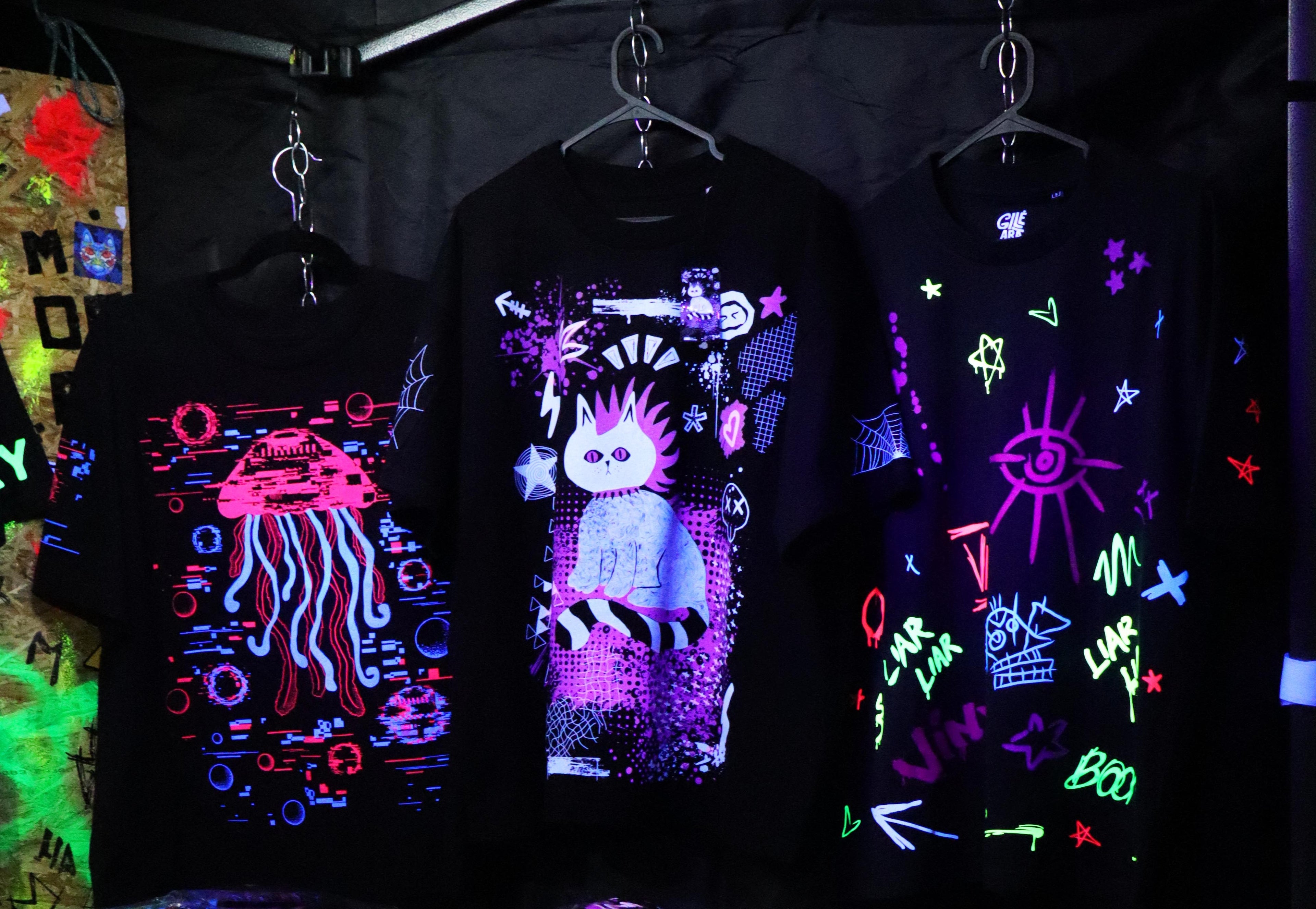 Neon-lit t-shirts on display in a dark setting