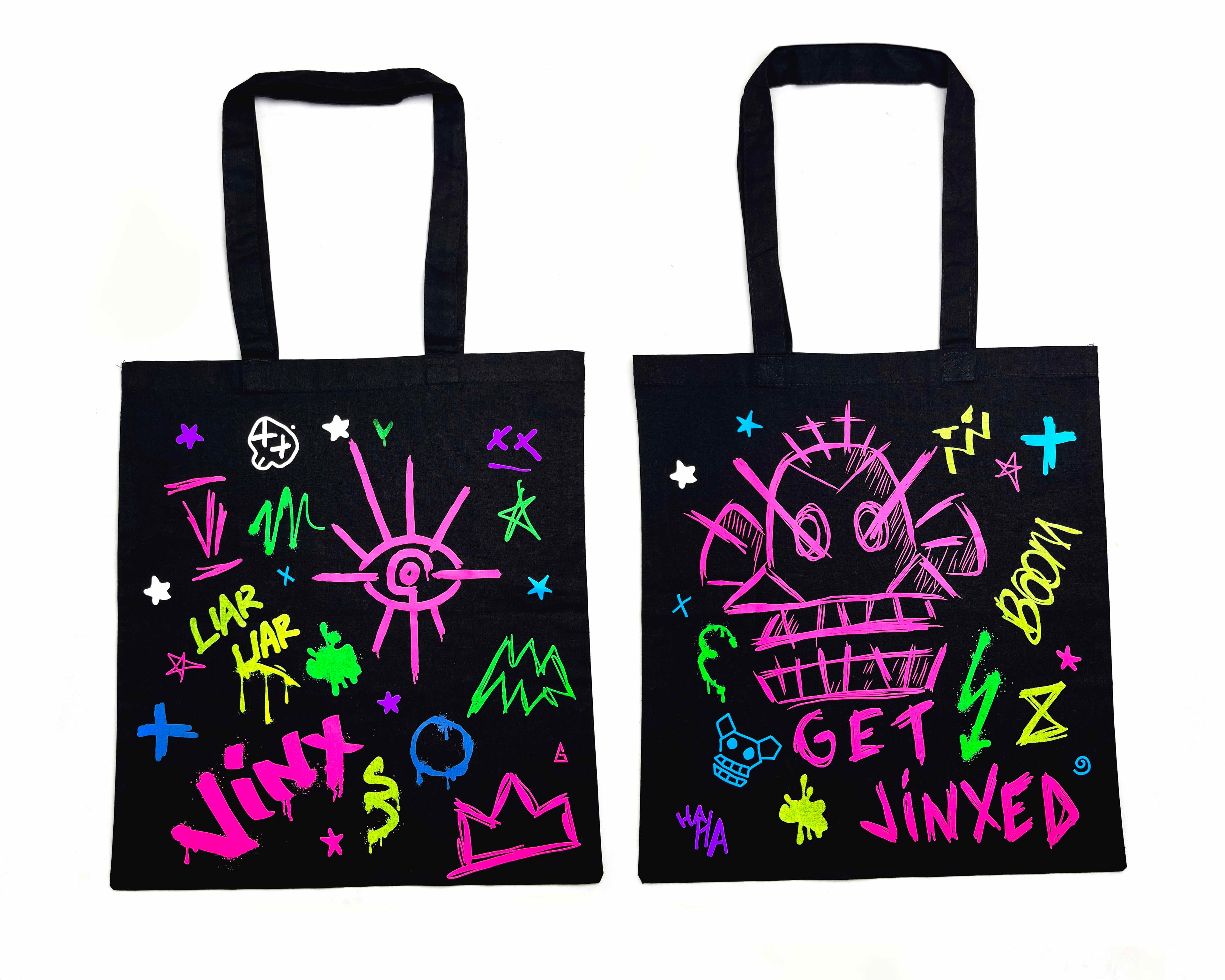 Two black tote bags with colorful designs and text on a white background