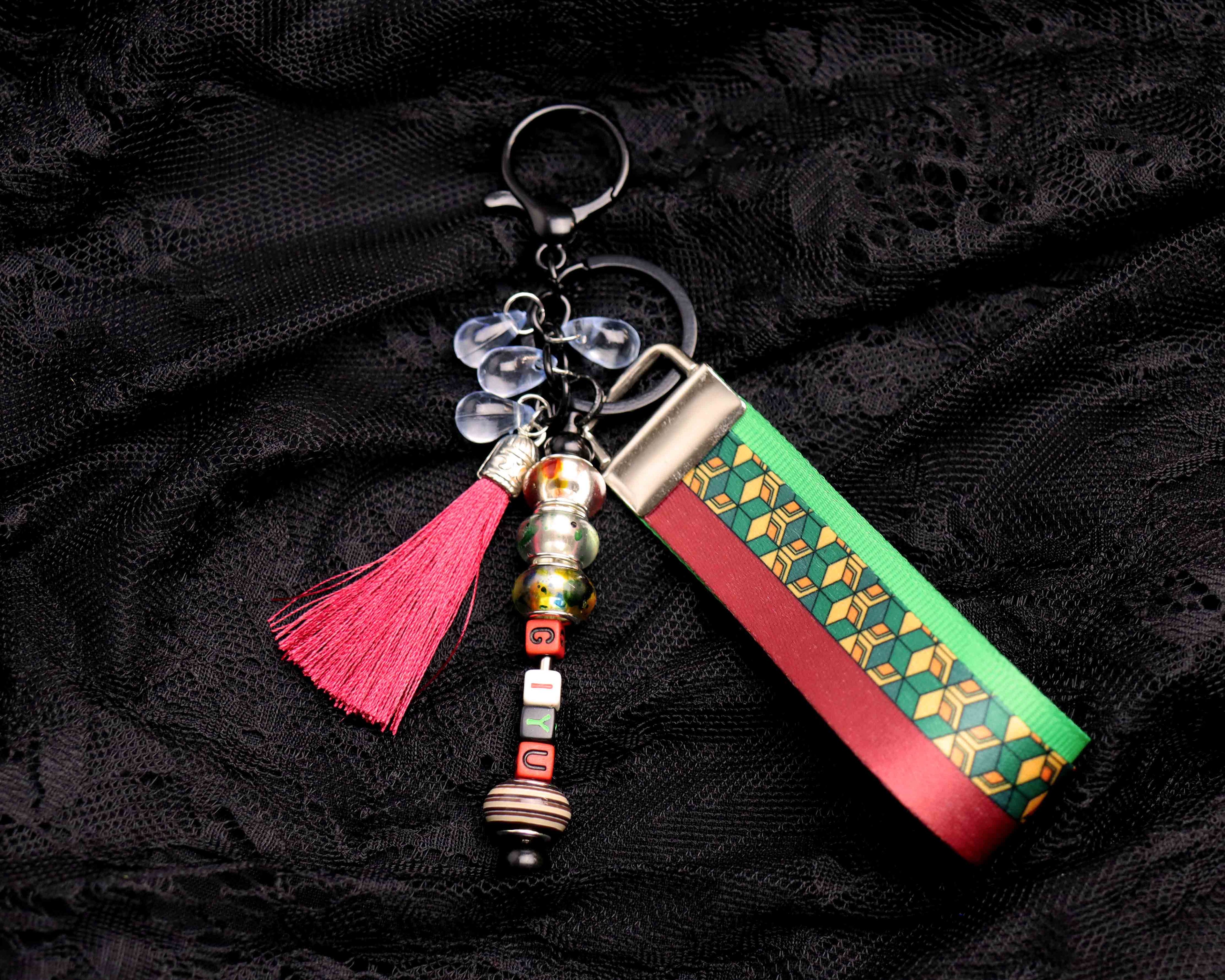 Decorative keychain with tassel and patterned design on a black fabric background