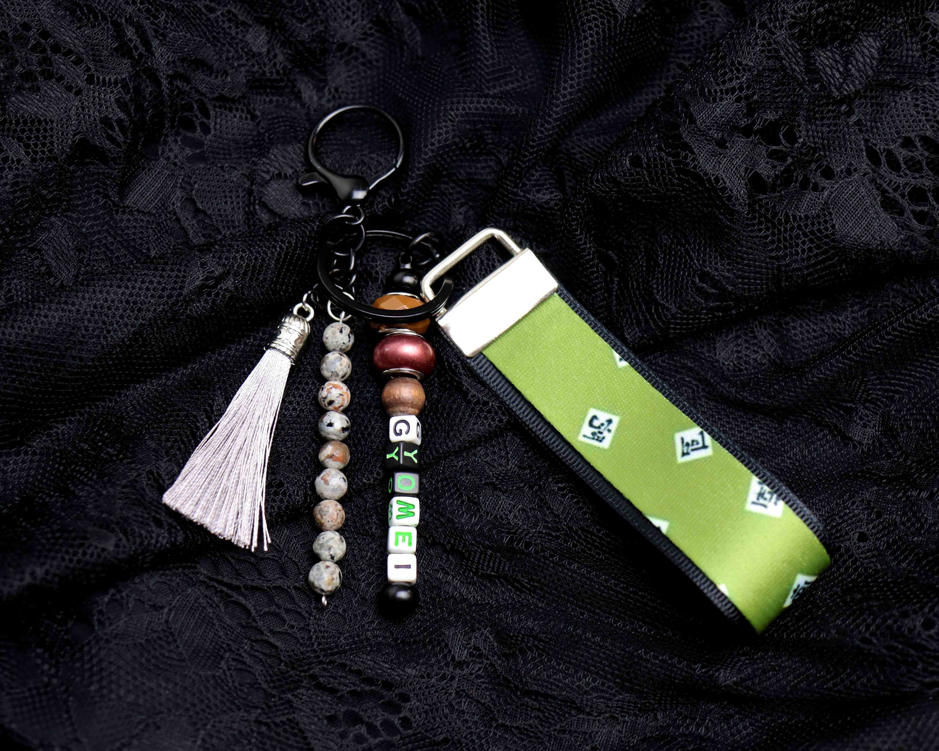 Green keychain pouch with tassel and beads on a black textured background