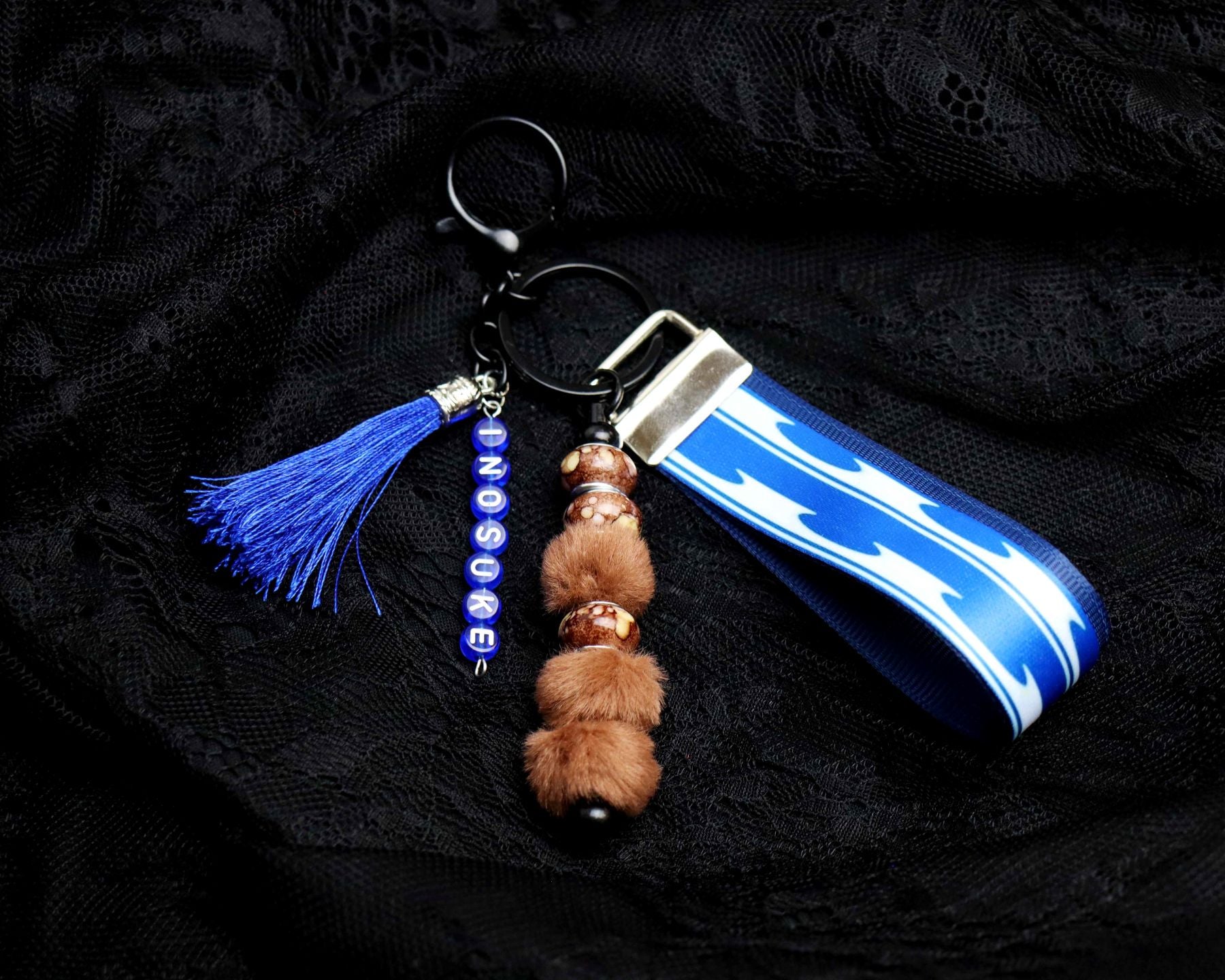 Keychain with tassel, beads, and blue and white striped object on a black background