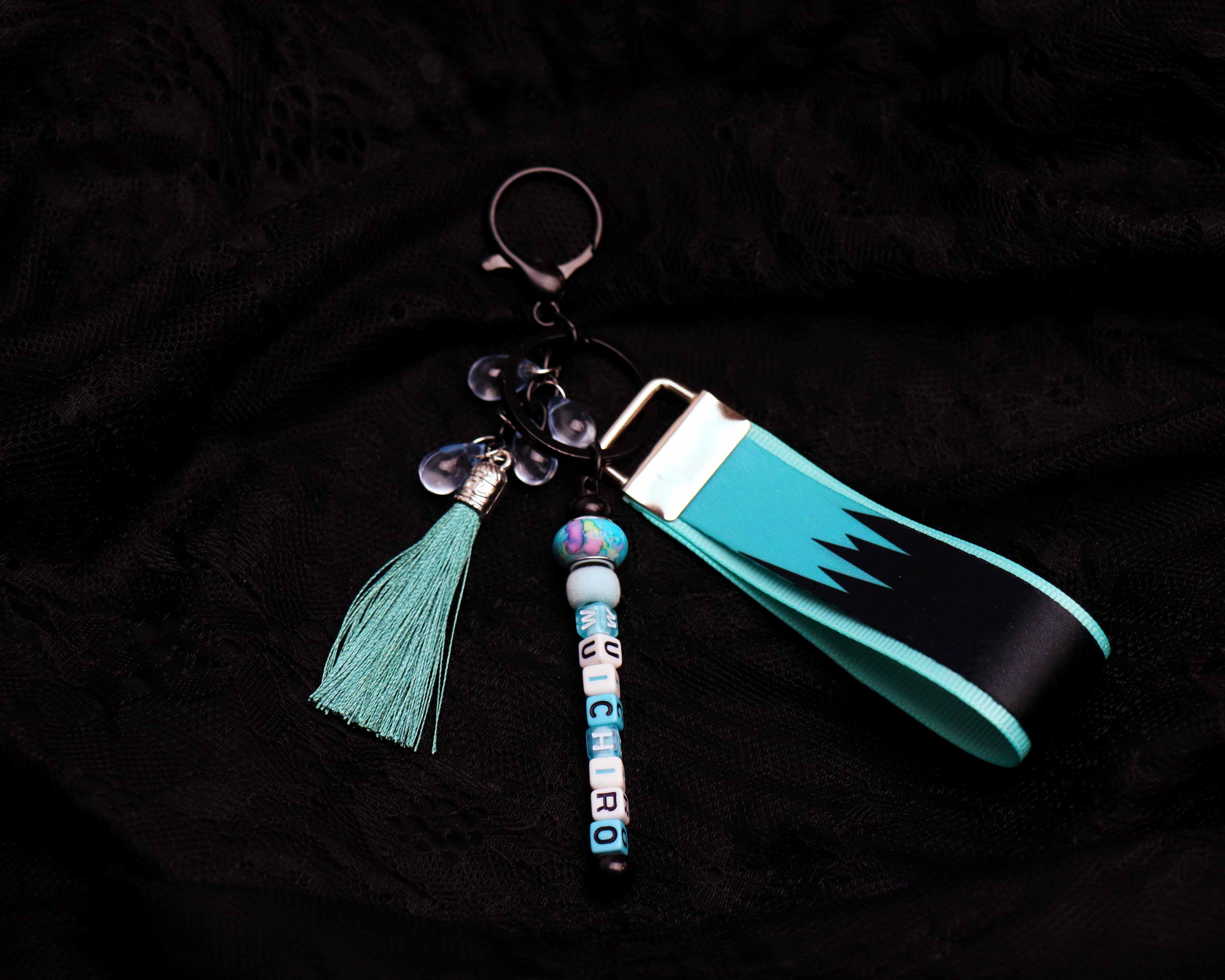 Keychain with turquoise strap, tassel, and beads on a dark background