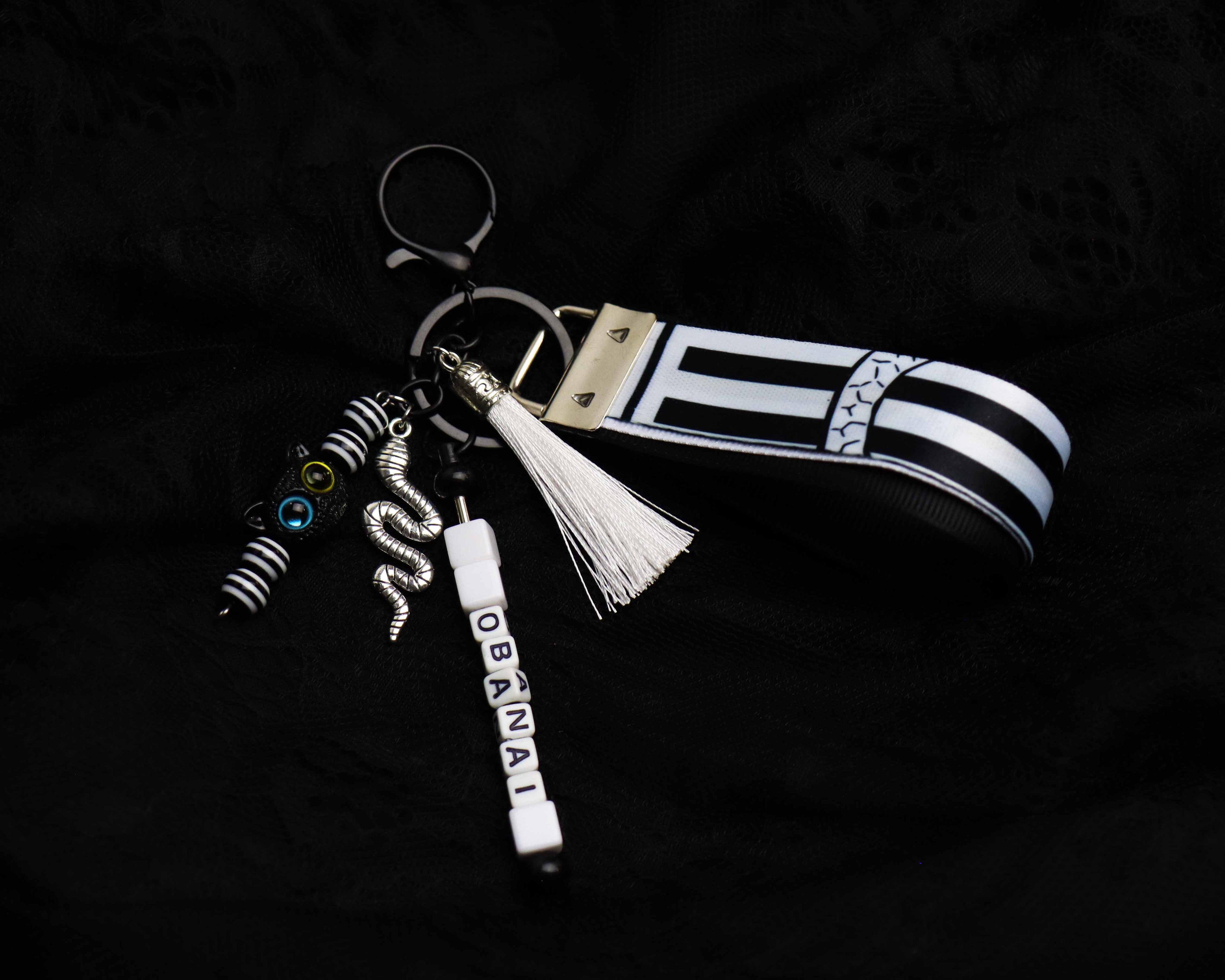 Keychain with black and white striped design, tassel, and 'Obama' charm on a dark background