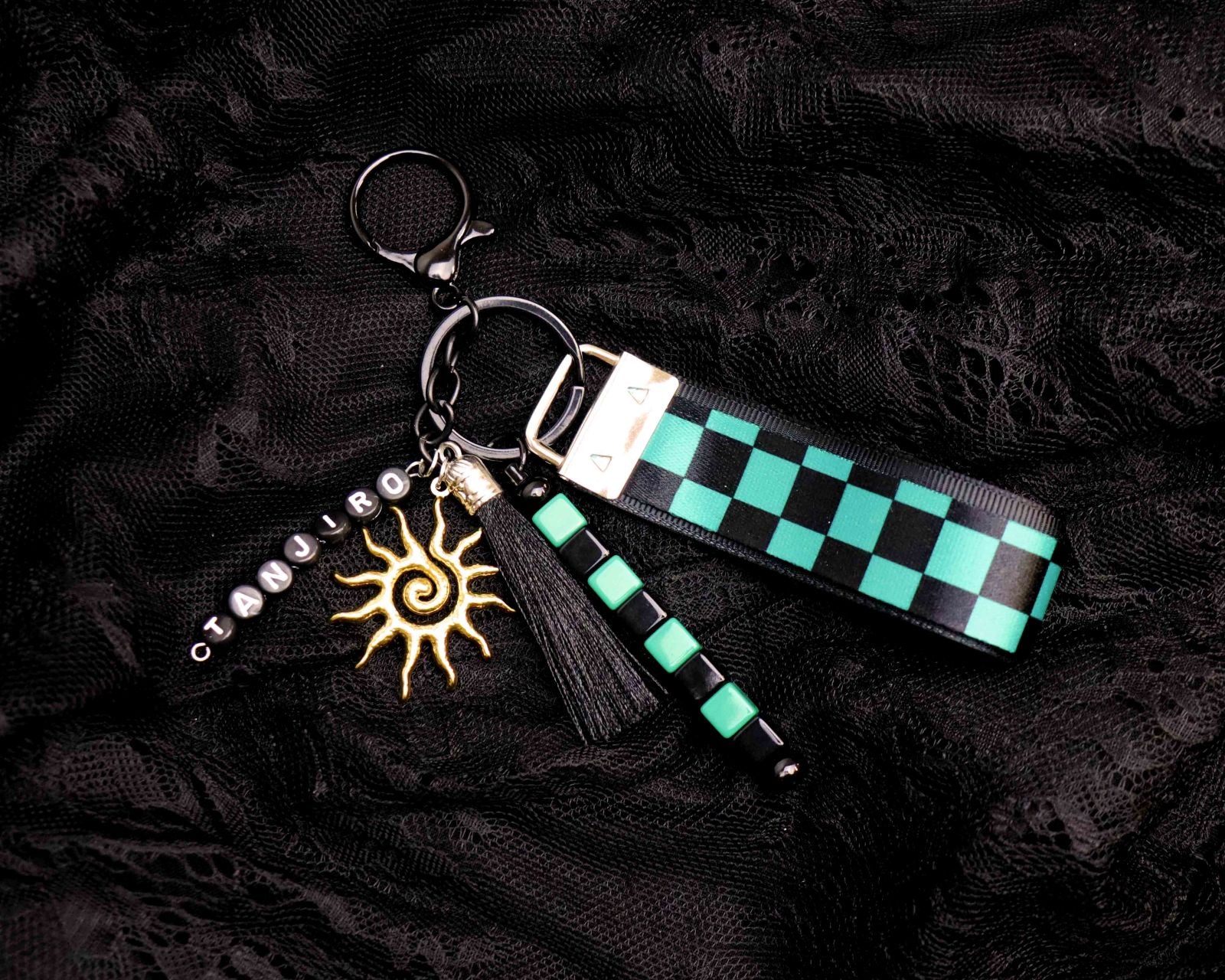 Keychain with green and black checkered strap and sun charm on a dark textured background