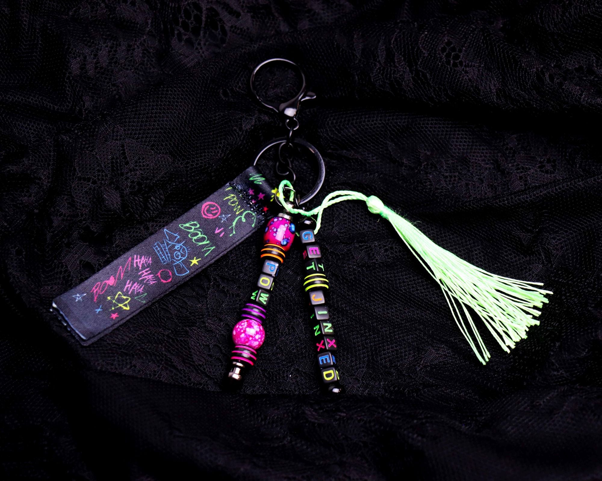 Glowing keychain with colorful beads and tassel on a black background
