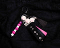 Keychain with pink and white beads, tassel, and decorative elements on a black background