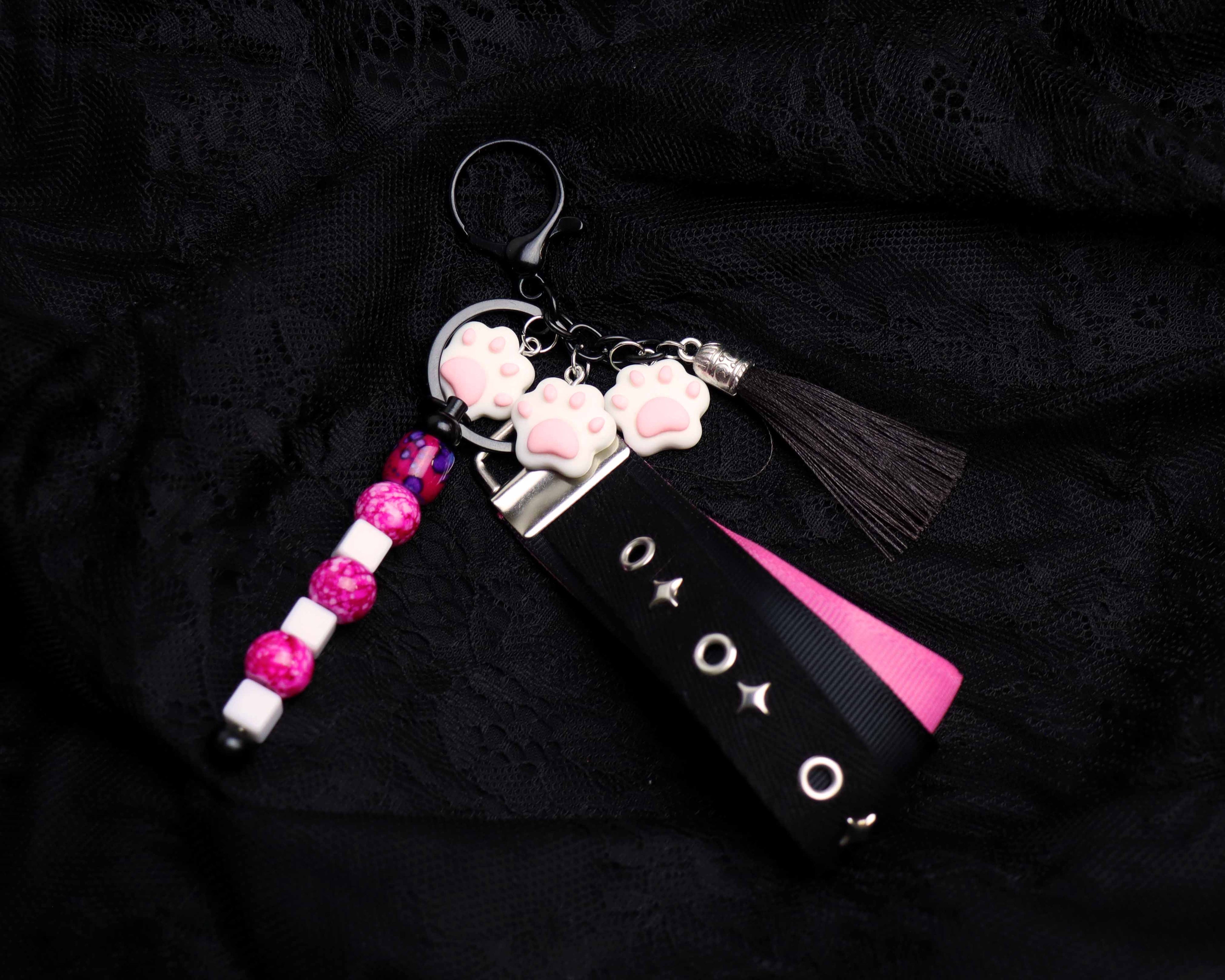 Keychain with pink and white beads, tassel, and decorative elements on a black background