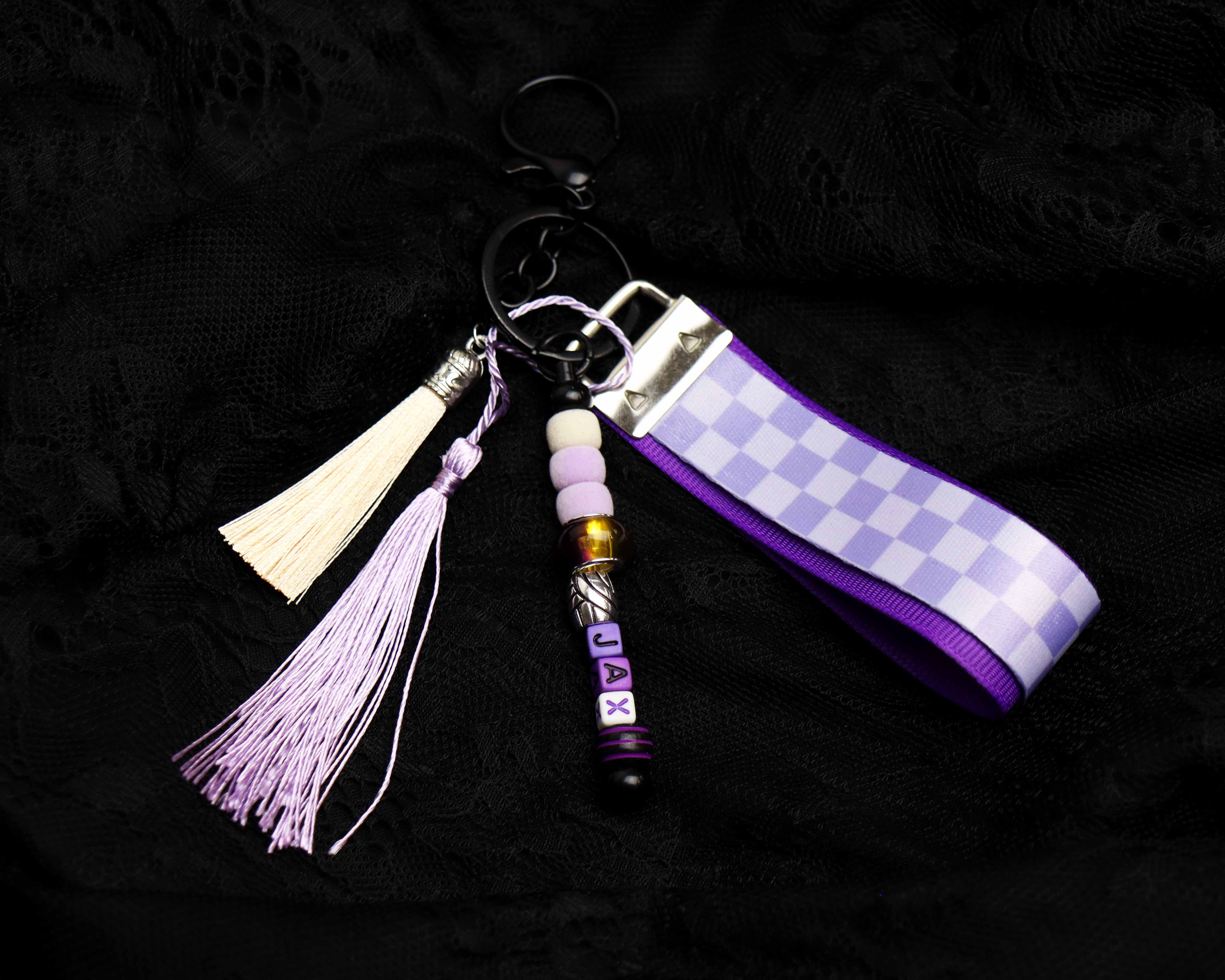 Keychain with checkered strap, tassel, and beads on a dark background