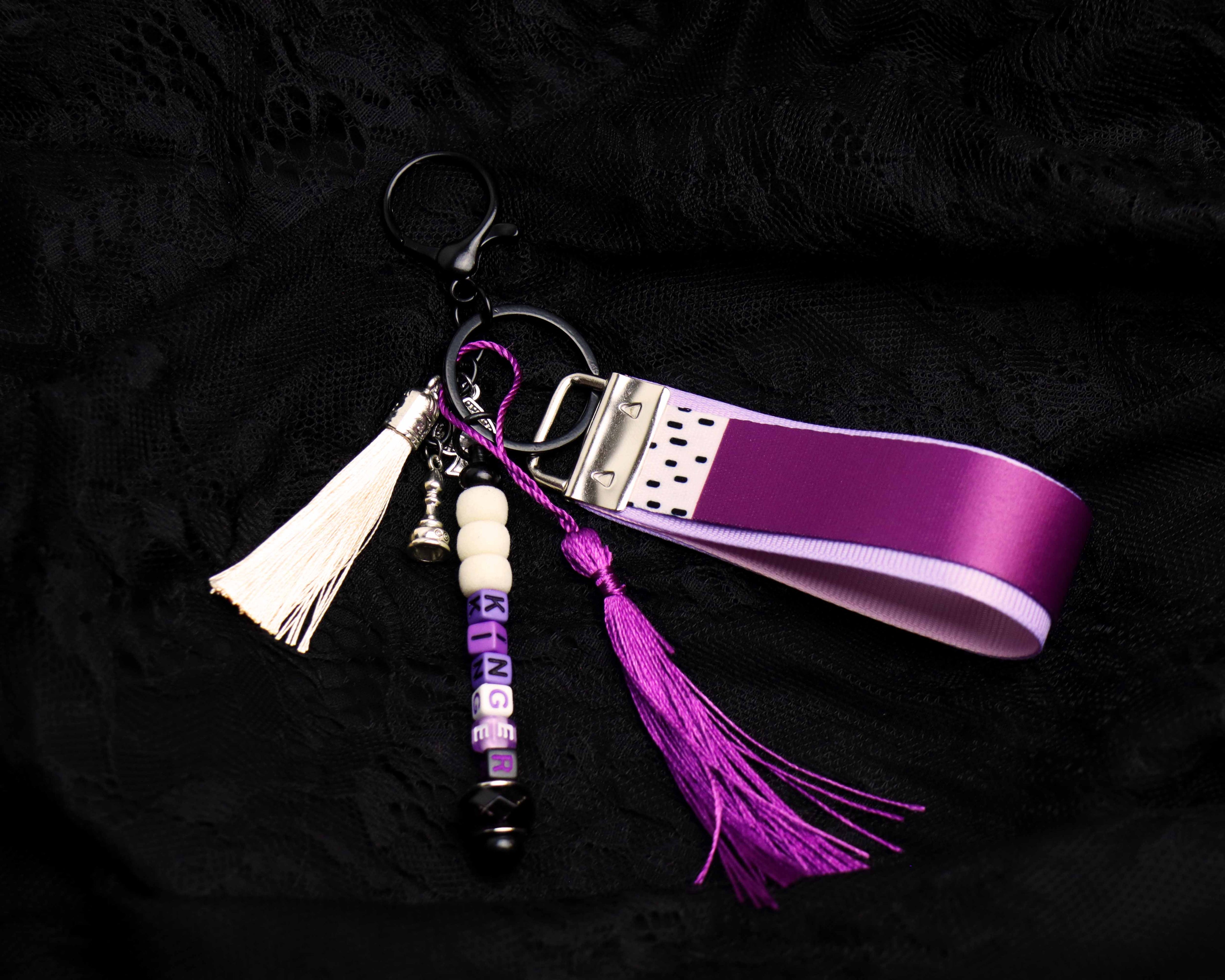 Keychain with purple ribbon and tassel on a black background