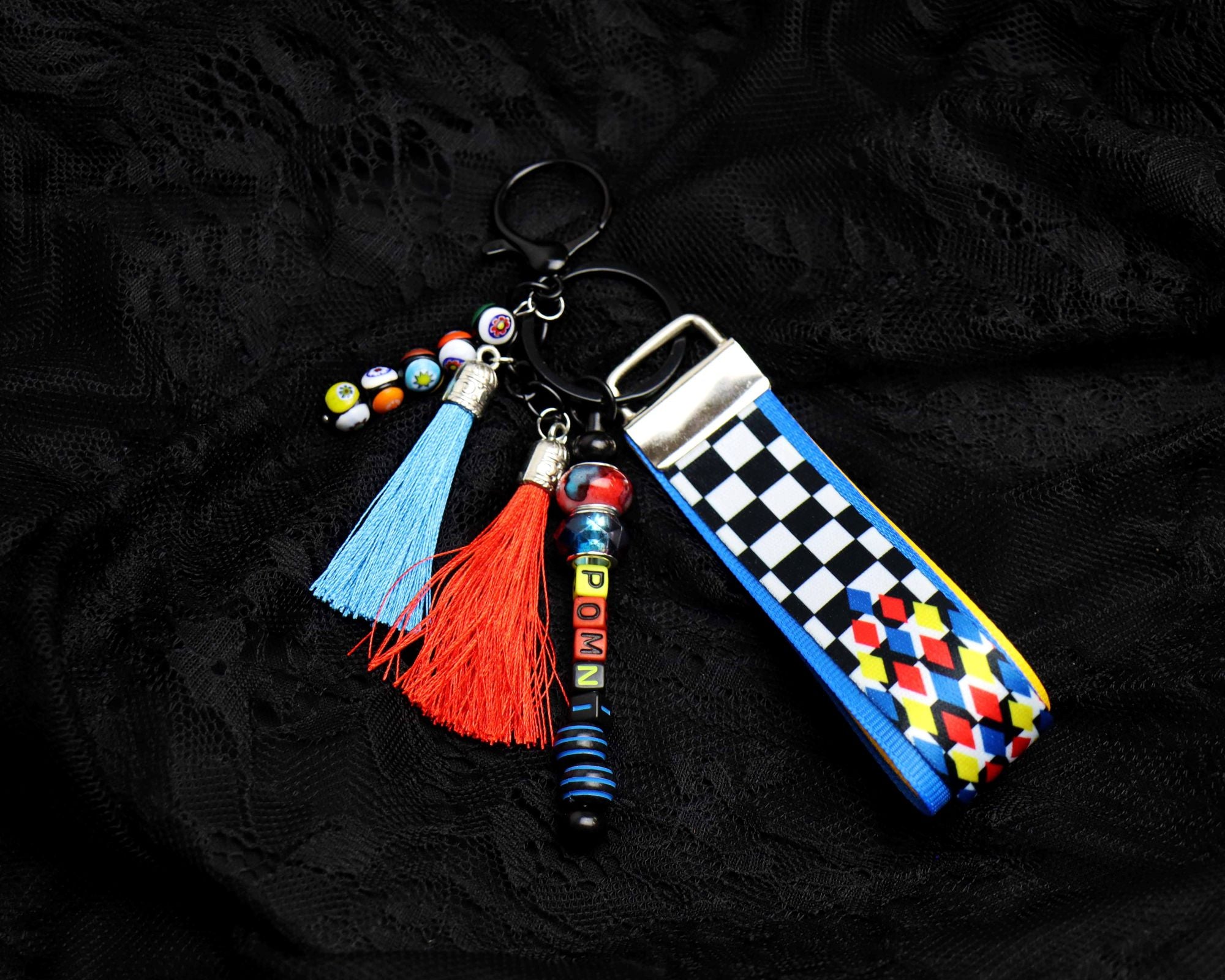 Colorful keychain with tassels and checkered strap on a black background